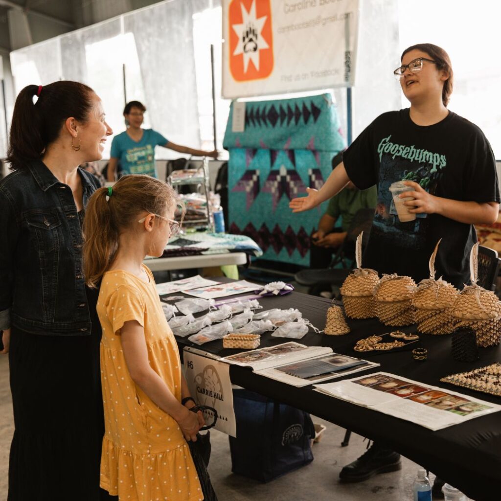 A woman and child buying are from a vendor at the Akwesasne Art Festival.